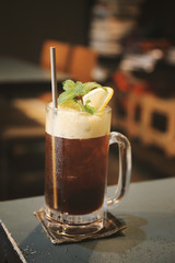 Iced cold brew coffee with lemon, toned image of cafe or coffee shop.