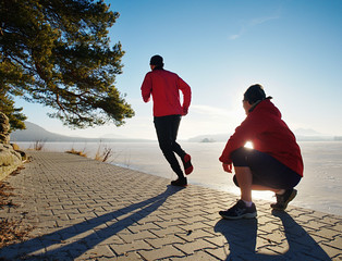 Woman watch running man.  They are training together at river