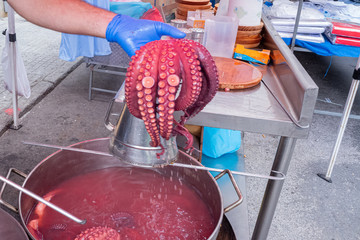 Pulpeiro enseñando tentáculos de pulpo a un cliente en la feria.