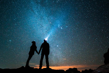 Night couple under the milky way with a torch