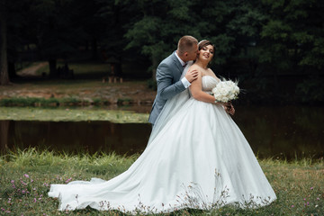 Couple in wedding attire with a bouquet of flowers and greenery is in the hands, the bride and groom. Walk the newlyweds. The bride and groom in nature. Wedding day. The best day of a young couple
