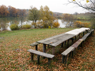 Autumn landscape based on Christian chronicles. Wooden table near the lake. On the opposite shore,...