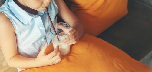 Little asian girl drinking water from glass via straw