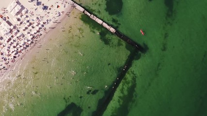 Aerial timelapse top view of a beach life during sunny summer day. A lot of people swimming in water