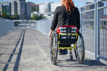 Obraz premium Young woman in wheelchair on a bridge