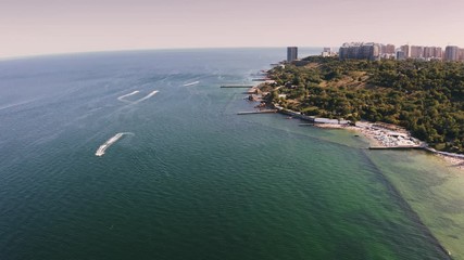Aerial shot of a sea coast line during summer sunny day, boats are passing by