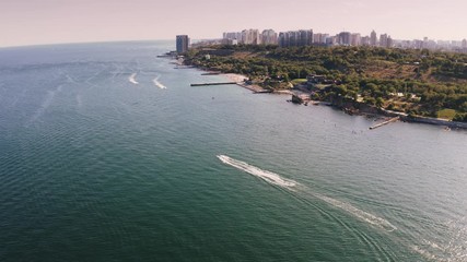 Aerial shot of a sea coast line during summer sunny day, boats are passing by