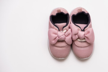 On a white background pink baby female sneakers, copy space