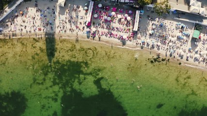Aerial top view of a beach life during sunny summer day. A lot of people swimming in water