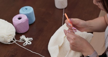Woman hands starting knitting with crochet hook and beige yarn
