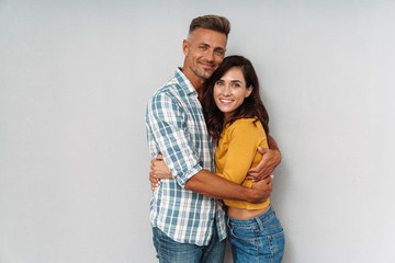 Cheerful happy adult loving couple isolated over grey wall background.