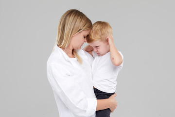 Young mother holding her crying child boy in her arms. The son is ill and feels bad, the woman is...