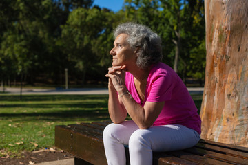 Thoughtful lonely old lady waiting someone in park. Senior grey haired woman in casual sitting on...