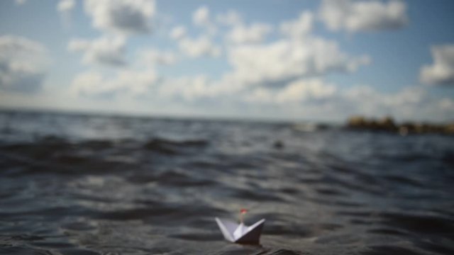 kleines Papierschiff in gro&szlig;en Wellen