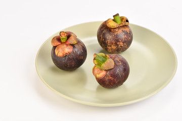three Fruit mangosteen fruits with a stone on a plate on a light background