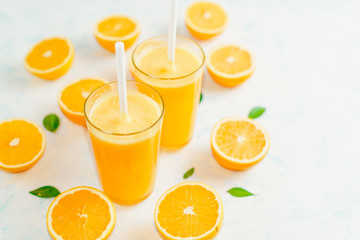 Orange juice and orange fruits with green leaves on white background.