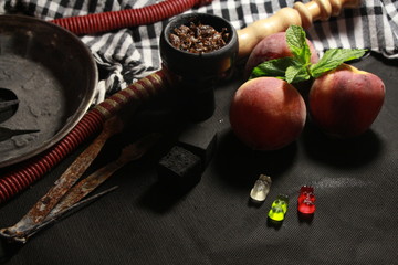 bowl with tobacco for hookah. fruits on a black background. smoking hookah