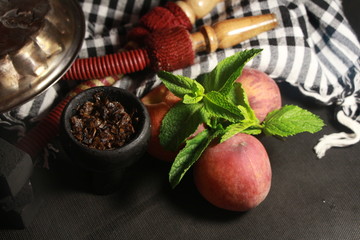 Obraz na płótnie Canvas bowl with tobacco for hookah. fruits on a black background. smoking hookah