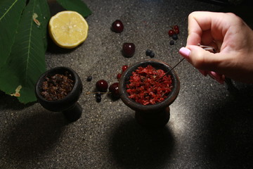 bowl with tobacco for hookah. berries on a black background