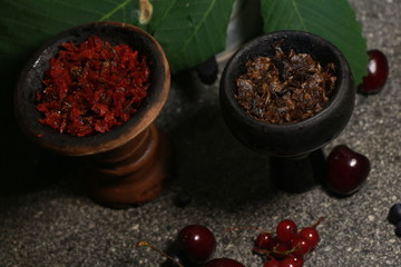 bowl with tobacco for hookah on a dark background. berries on a black table. hooka smoking