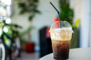 Close up of an ice coffee in a plastic cup with a straw in it.Nice bokeh background.