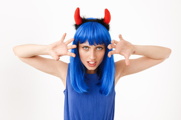 Portrait of young aggressive woman wearing blue wig and toy horns playing role of devil