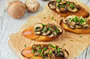 Champignon or brown cap mushroom Crostini on brown paper and wooden board.