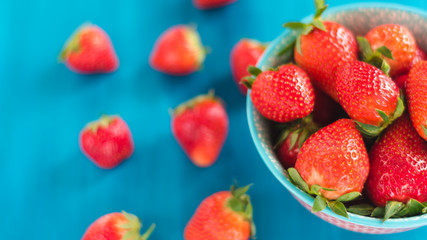 bright printed bowl of fresh strawberries on blue wooden background