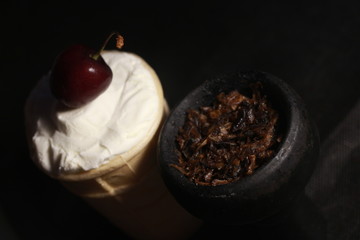 bowl with tobacco for hookah. fruits and berries on a black background. smoke hookah
