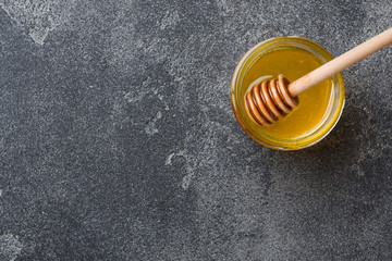 Liquid honey and honey stick on a gray background copy space.