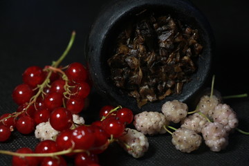 bowl with tobacco for hookah. fruits and berries on a black background. smoke hookah