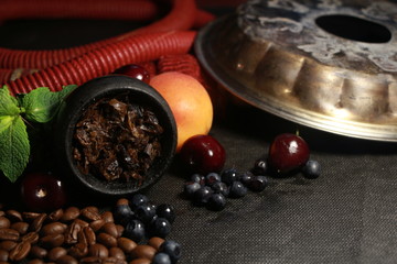 bowl with tobacco for hookah. fruits and berries on a black background. smoke hookah