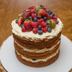 Three tiered birthday cake with fruit toppings.