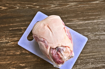 Frozen Whole Duck on board on wooden background.