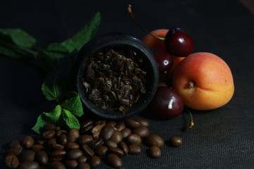 bowl with tobacco for hookah. fruits and berries on a black background. smoke hookah