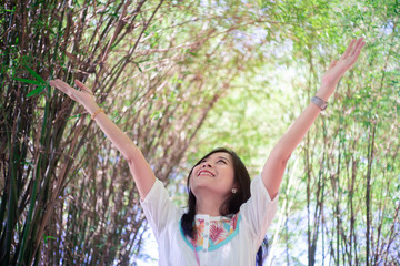 Freedom woman arms raised enjoying the fresh air in green bamboo trees.