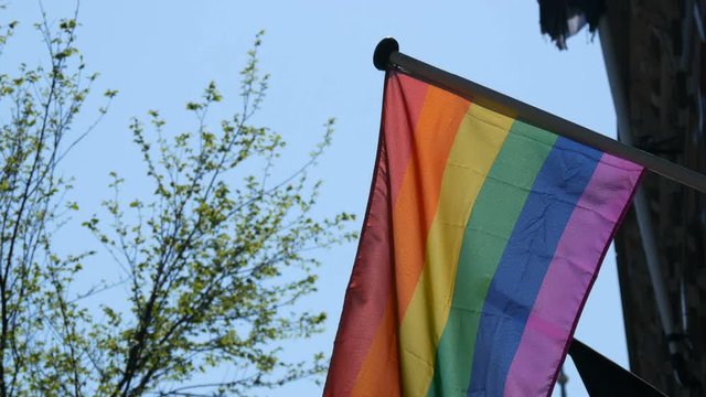 Gay pride rainbow flag LGBT flying. A multi-colored rainbow flag, a symbol of unconventional traffic, sways in the wind in the capital of the Netherlands, Amsterdam