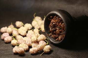 bowl with tobacco for hookah. fruits on a black background. smoking hookah