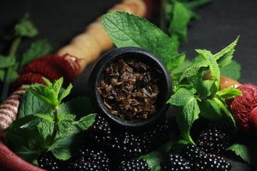 bowl with tobacco for hookah. fruits on a black background. smoking hookah