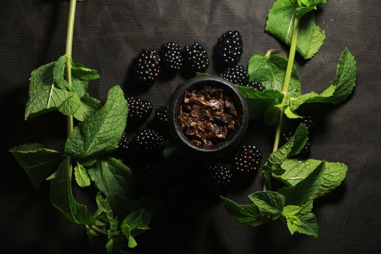 bowl with tobacco for hookah. berries on a black background. smoking sheesha