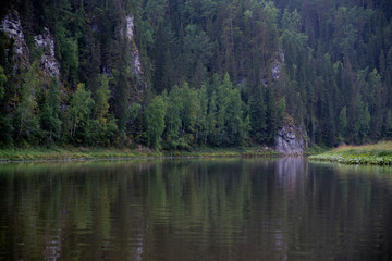The river against the backdrop of mountains and forests in cloudy weather.