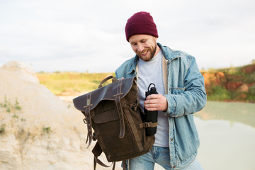 Tourist traveling through the canyon pulls out of a backpack thermos of drinking water