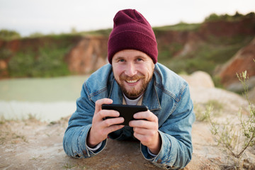 A man in nature flips through the mail and gets good news. Laughs and types a text message on the phone