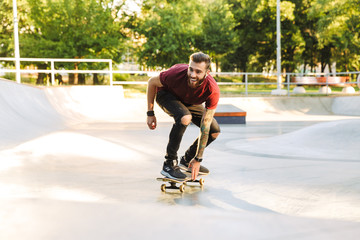 Happy young man riding on a skateboard at the ramp