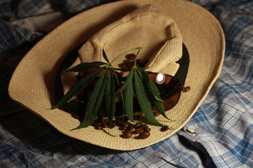 straw hat, glasses and leaves of marijuana on a black background