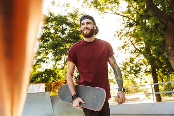 Happy cheerful young man walking at the skate park ramp