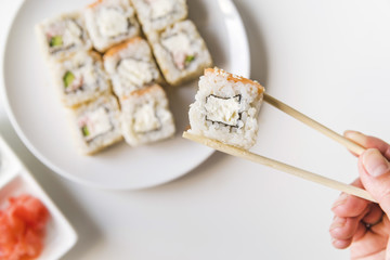 Chopsticks holding a sushi roll