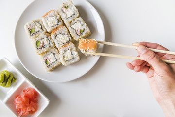 Hand with chopsticks grabbing a sushi roll