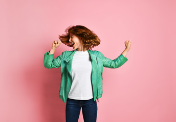 woman wearing jeans and a jacket is shaking her head with her hair. The concept of joy, happiness,...