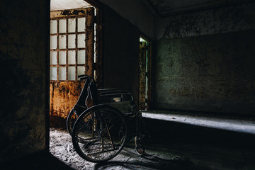 Fototapeta na wymiar Spooky Derelict Wheelchair in Dark Hallway - Abandoned Creedmoor State Hospital - Queens, New York City, New York